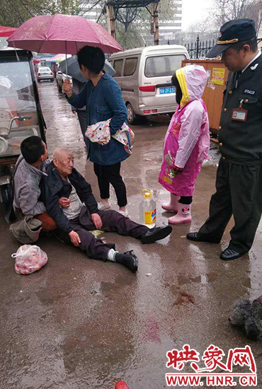 女孩為倒地老人撐傘。