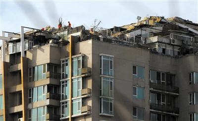 　　昨日，身穿橘黃色馬甲的工作人員在人濟(jì)山莊樓頂拆除違章建筑。新京報(bào)記者 吳江 攝