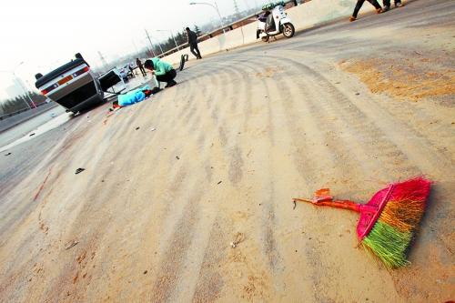 被撞的環(huán)衛(wèi)工躺在地上，身上蓋著藍(lán)色布?jí)K，現(xiàn)場(chǎng)除散落的汽車碎片外，還留有被撞斷的掃帚。