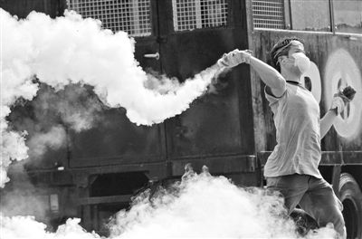 12月2日，泰國曼谷，一名反政府示威者在總理府附近向負責執(zhí)勤的警察投擲催淚彈。英拉請求示威者不要再試圖占領政府工作部門，不要逼迫政府工作人員選邊站。