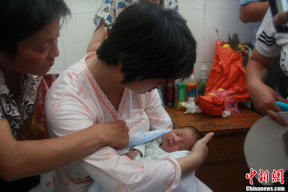 圖為久別重逢，獲救嬰兒母親悉心撫摸愛子。張一辰 攝