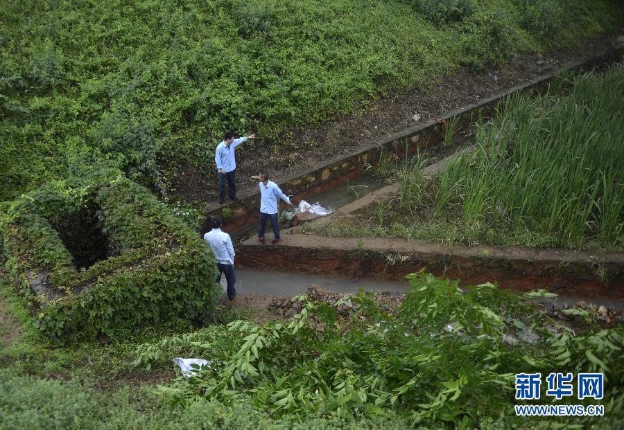 5月18日，工作人員在槽罐車泄漏現(xiàn)場附近的水渠邊查看情況。