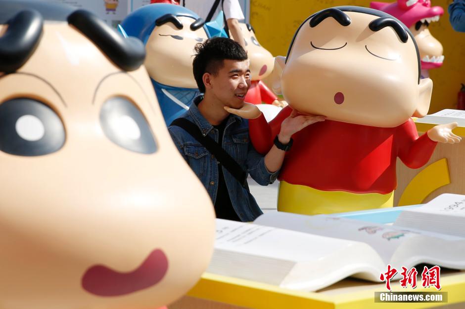 4月22日，游客與蠟筆小新合影?！跋灩P小新25周年紀(jì)念特展”日前在北京開展，吸引了不少市民游客。