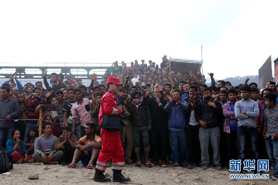 圍觀的尼泊爾民眾在中國(guó)國(guó)際救援隊(duì)成功搜救出幸存者后向搜救隊(duì)員歡呼致意。
