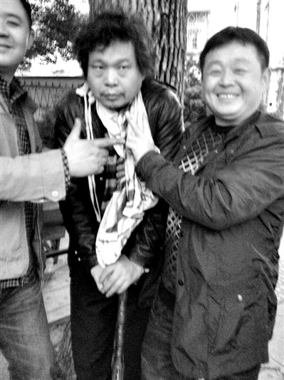 兩名接訪(fǎng)人員與患有癌癥的訪(fǎng)民段新德合影時(shí)，面帶笑容擺出勝利的手勢(shì)。