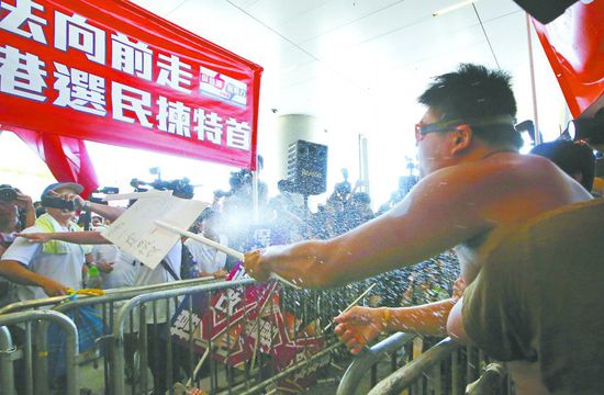 17日，在香港立法會(huì)外，一名反對(duì)政改的男子向支持派人群投擲標(biāo)牌。