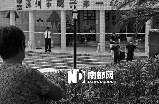 →7月19日，鵬興花園第一幼兒園門前，民警在現(xiàn)場進行完勘查取證后，園長和保安的尸體被運走。南都記者 徐文閣 攝