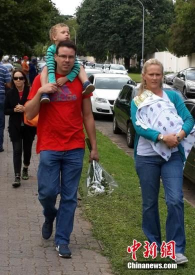 圖為一個(gè)白人家庭，由父母帶著孩子到曼德拉家門外悼念。中新社發(fā) 宋方燦 攝
