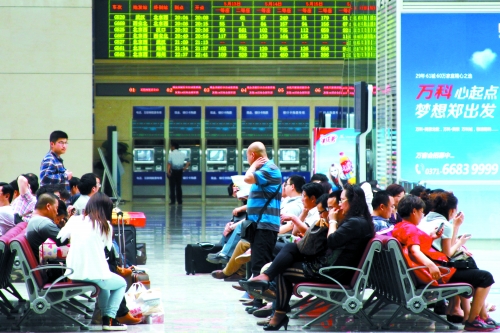 候車大廳溫度很高，一名乘客一手扇風(fēng)、一手擦汗