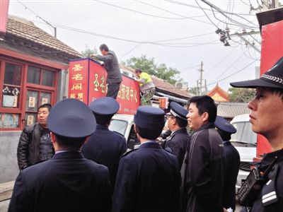 昨日下午,東城區(qū)工商、城管、公安等部門,對雍和宮附近的預(yù)測中心進(jìn)行清理整頓,站在車頂?shù)膬擅と苏鸪患摇邦A(yù)測中心”的招牌。因雍和宮、白云觀等文化景點外聚集大量算命先生,被媒體稱為“算命一條街”。本版攝影/新京報記者 李寧 攝