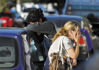 27日，遇難者親友在火災現(xiàn)場旁哭泣。