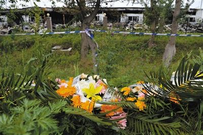 昨日，吉林省德惠市吉林寶源豐禽業(yè)有限公司燃燒事故現(xiàn)場警戒線外，遇難者家屬在路邊擺放了花圈祭奠逝去的親人。吳江 攝