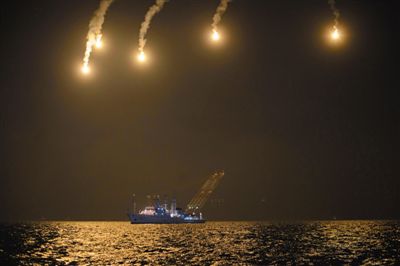 22日，搜救人員在照明彈的光亮下連夜搜救。