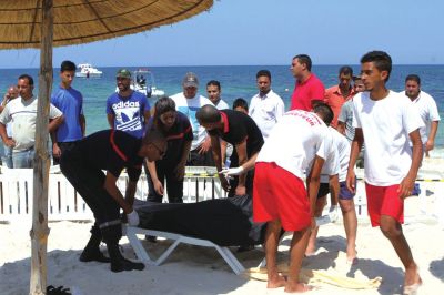6月26日，在突尼斯蘇塞，救生員和醫(yī)務(wù)人員在發(fā)生襲擊事件的海灘運(yùn)送一名死者的遺體。新華社發(fā)