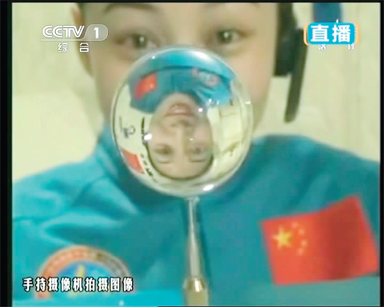 王亞平的倒影出現(xiàn)在水球中。新華社發(fā)（視頻截圖）