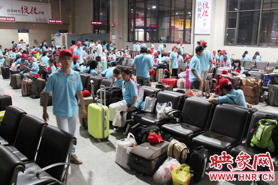 大學(xué)生志愿者在火車站候車室內(nèi)整裝待發(fā)。