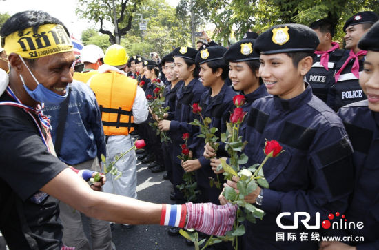 2013年12月03日,曼谷總理府與曼谷警署允許反政府示威民眾進(jìn)入,雙方進(jìn)入暫時“停戰(zhàn)”狀態(tài)迎接泰王生日。曼谷警察總署,女警們手持鮮花送給反政府示威民眾。圖片來源:Manish Swarup/東方IC
