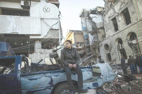 埃及曼蘇拉市警察局24日遭汽車炸彈襲擊，被疑是穆兄會(huì)的報(bào)復(fù)。圖為一名男子在被炸毀的警察局前。