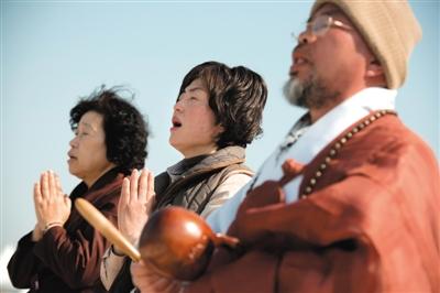 23日，一名僧侶引領人們?yōu)樗勒咂矶\。