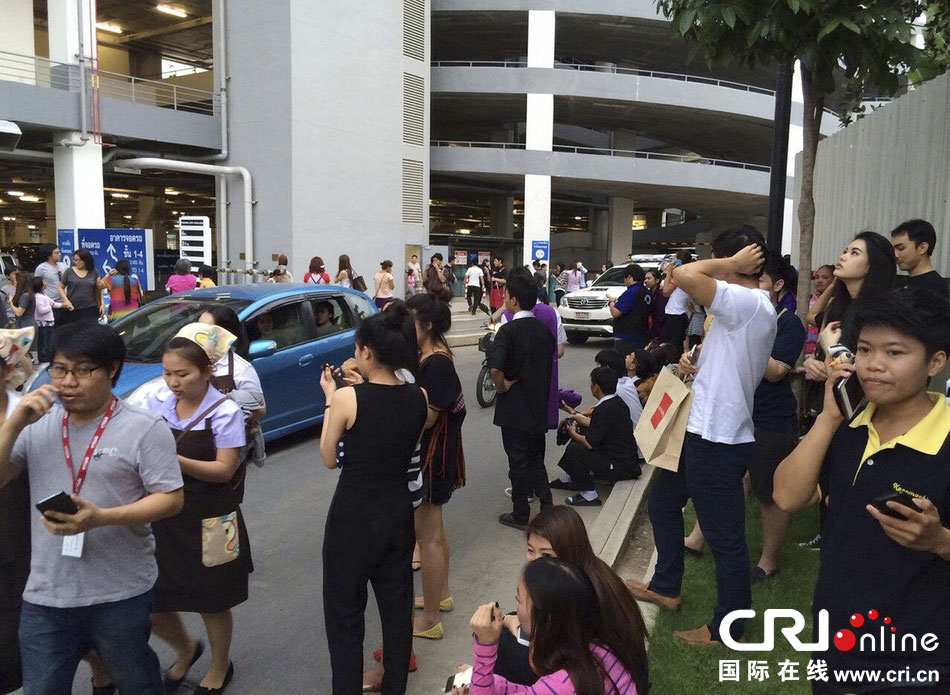 當(dāng)?shù)貢r(shí)間2014年5月5日，泰國(guó)清萊，工人們站在一棟大樓外避難。