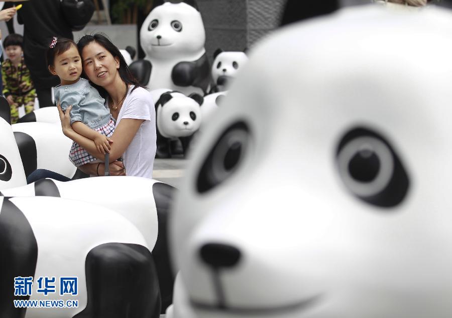 6月2日，一位家長帶著孩子在上海街頭和大熊貓模型合影。