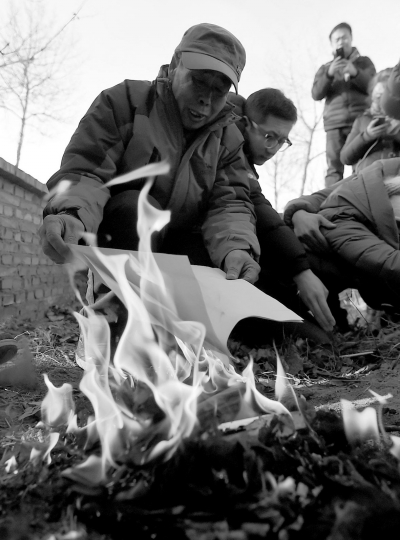 李三仁在兒子墳前焚燒再審無(wú)罪判決文書(shū)的復(fù)印件。新華社發(fā)