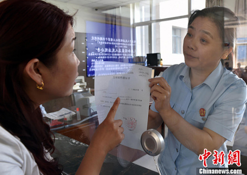 資料圖：2015年5月4日，河北石家莊市橋西區(qū)人民法院立案庭庭長齊燕正在為立案人辦理相關(guān)手續(xù)，完成整個(gè)過程只用了5分鐘。當(dāng)日是立案登記制改革首個(gè)工作日，該院共立案36件，立案率達(dá)到90%。中新社發(fā) 翟羽佳 攝