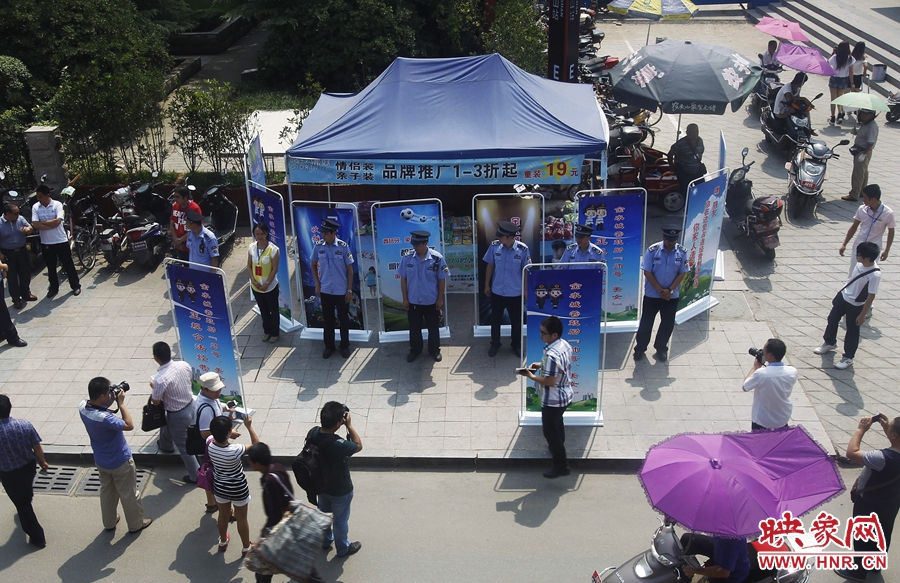 執(zhí)法人員用宣傳牌圍擋占道經(jīng)營(yíng)攤位。