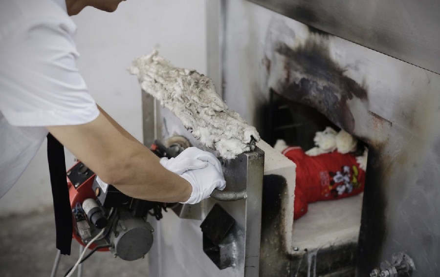 工作人員將狗狗推入火化爐。