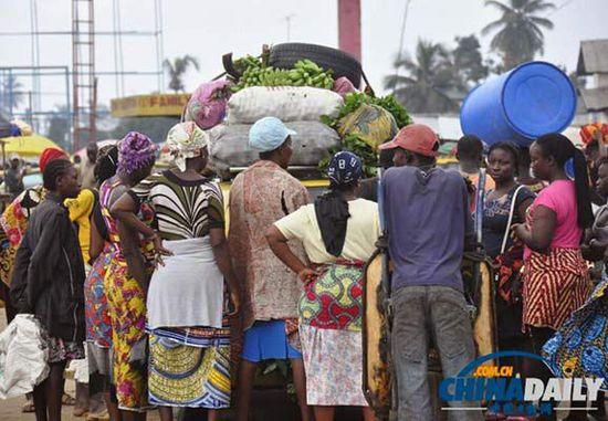 當(dāng)?shù)貢r間2014年8月14日，利比里亞蒙羅維亞，市場里的商人們圍著一輛汽車。