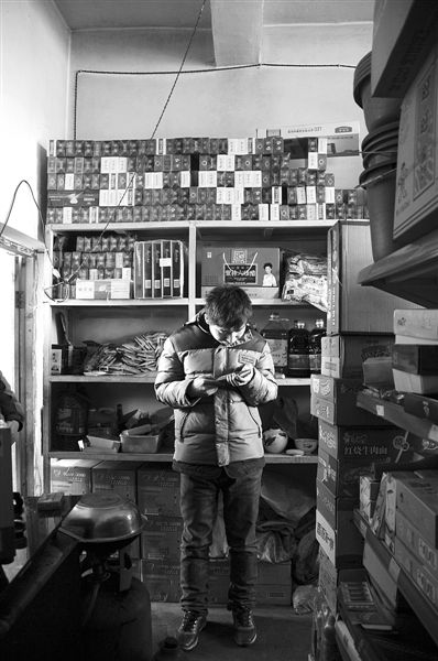 1月21日，周瑋在自家的超市里玩計(jì)算器。