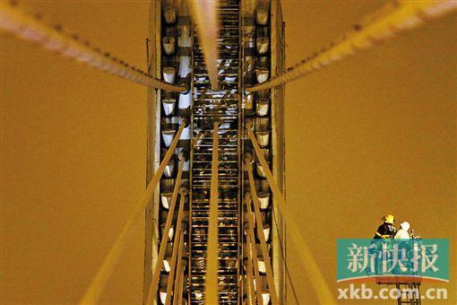 截至今日零時(shí)，男子仍未有下橋舉動(dòng)。圖為公安和消防人員乘消防云梯在高空上和男子交談。