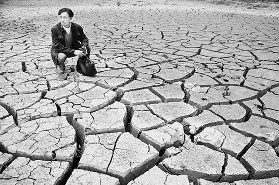 蹲在干涸的田地里，焦裕祿為饑餓的百姓揪心不已 《焦裕祿》劇照